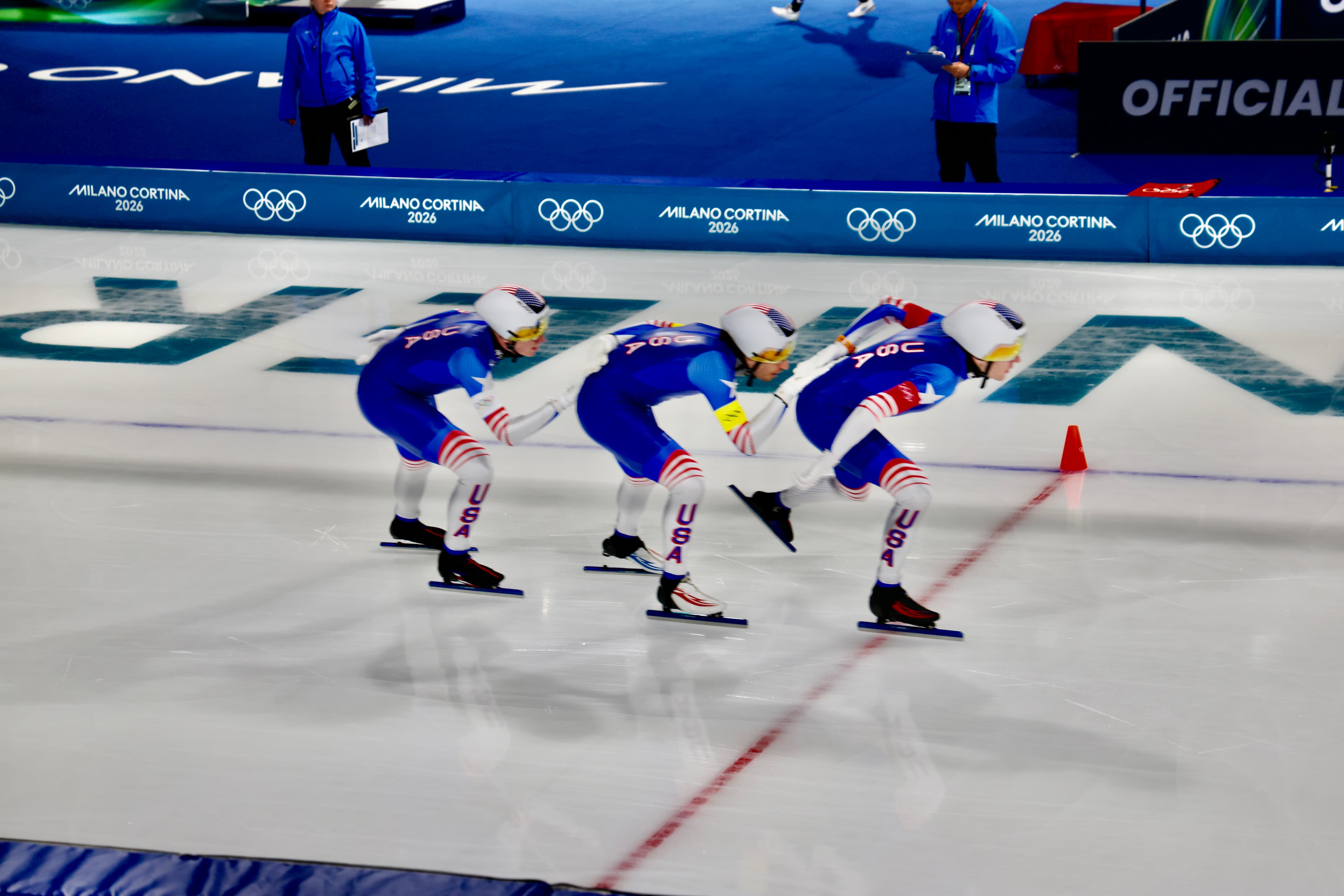 Three USA short track speed skaters in tight pursuit formation at Milano Cortina 2026